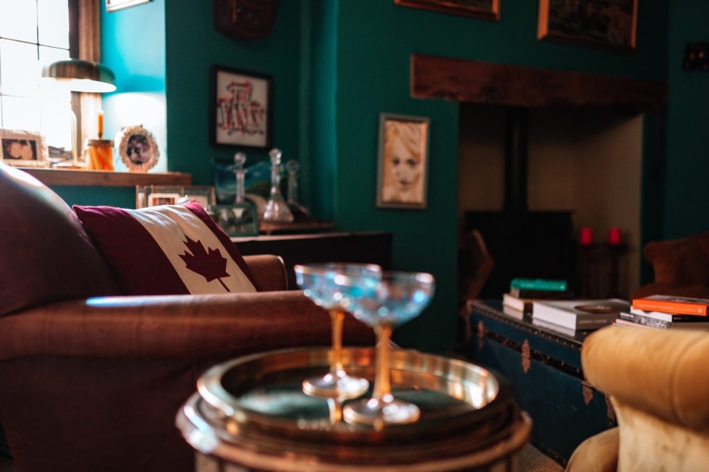 Warm and sophisticated snug focus on cocktail glasses by the sofas with fire place in background