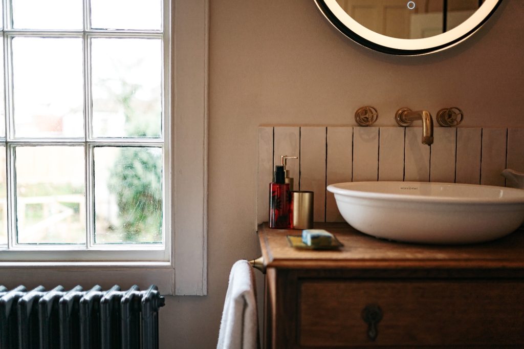 Bathroom with roll top bath, fireplace and feature red wall with images on sink area